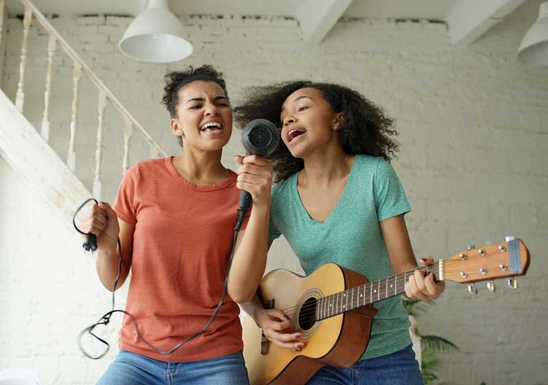 Happy couple enjoying at-home karaoke date night with microphone and acoustic guitar in living room